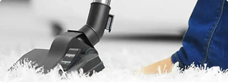 Close-up of a professional vacuuming a white carpet in Sun Valley.