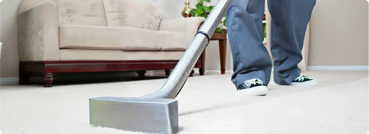 Carpet cleaning technician using a hot-water extraction wand on a light-colored carpet in a living room, Reno, NV.