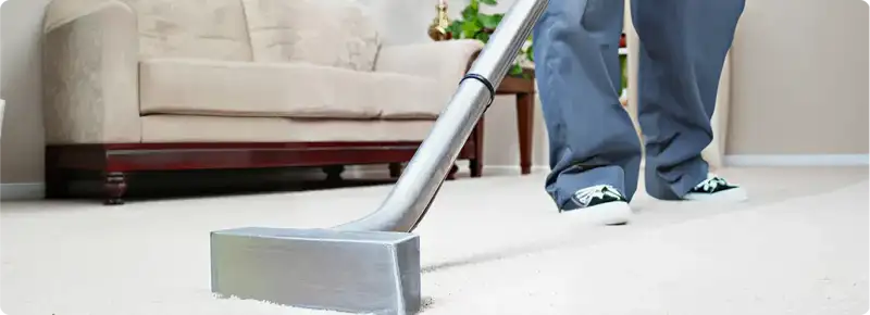 Carpet cleaning technician using a hot-water extraction wand on a light-colored carpet in a living room, Reno, NV.