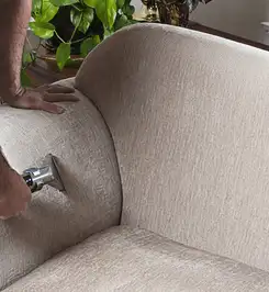 Professional upholstery cleaner deep-cleaning a fabric sofa with a handheld extraction tool and hose Reno, NV.